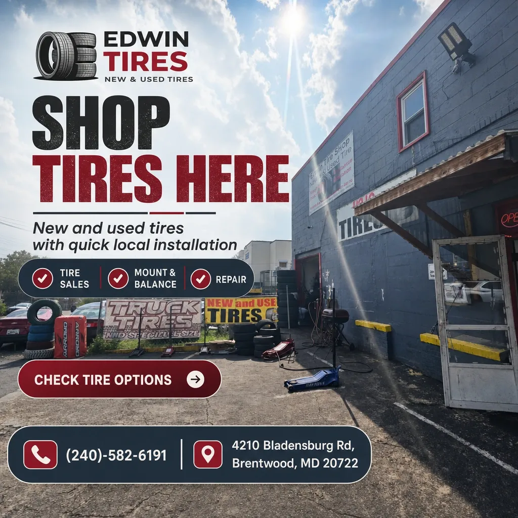 Front exterior of Edwin Tires shop with stacked tires, large 'Shop Tires Here' signage, service bay and open door under a sunny sky