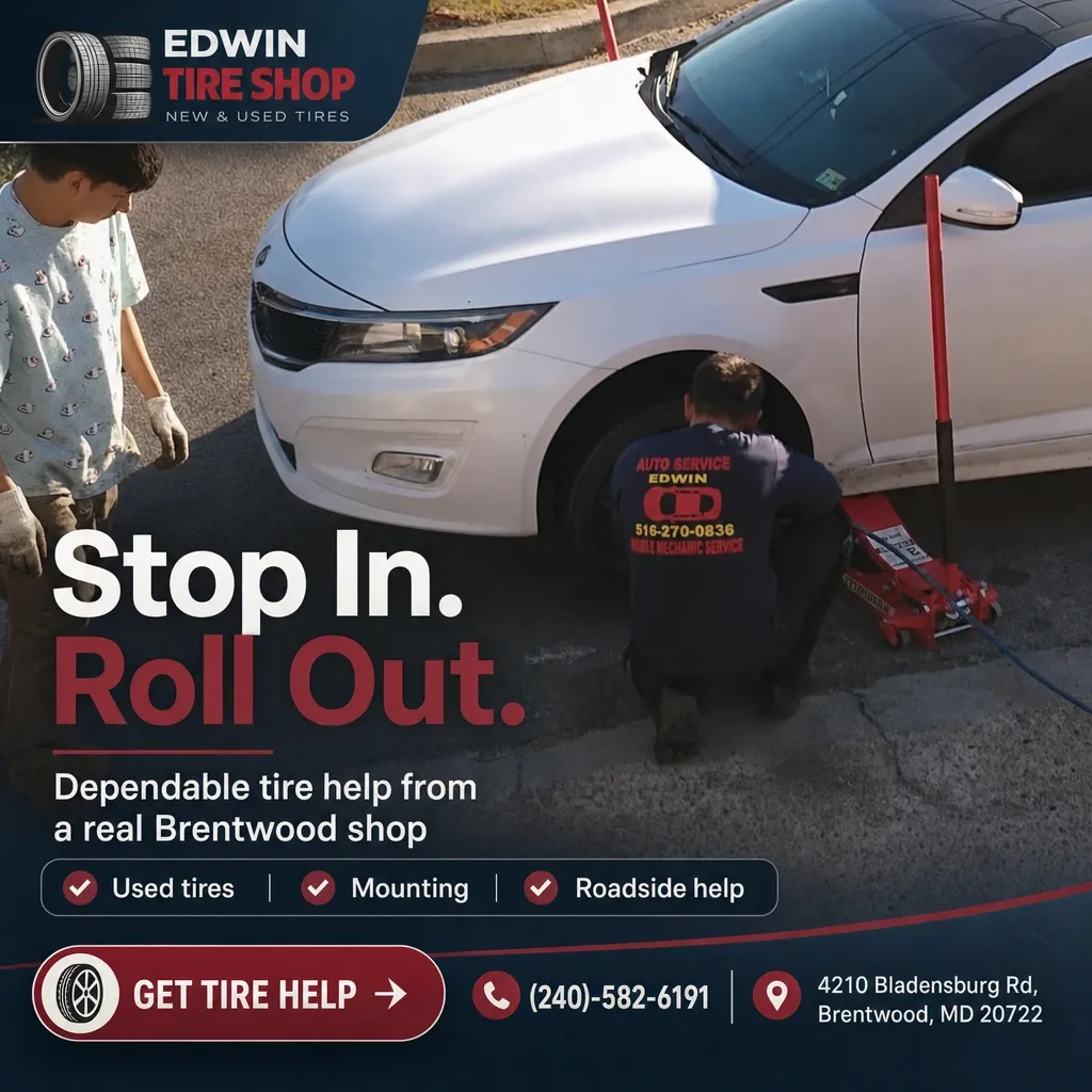 Edwin Tire Shop mechanic kneeling by a white car changing a tire at the roadside while a customer watches.